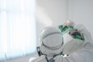 Disinfecting of office to prevent COVID-19, person in white hazmat suit with disinfect in office, coronavirus concept