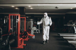 Cleaning and Disinfection in crowded places amid the coronavirus epidemic Gym cleaning and disinfection Infection prevention and control of epidemic. Protective suit and mask and spray bag